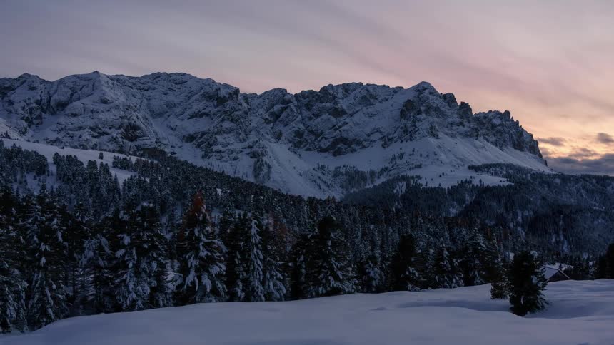 Time lapse of a pine tree forest on a snowcovered landscape in the mountains at sunset