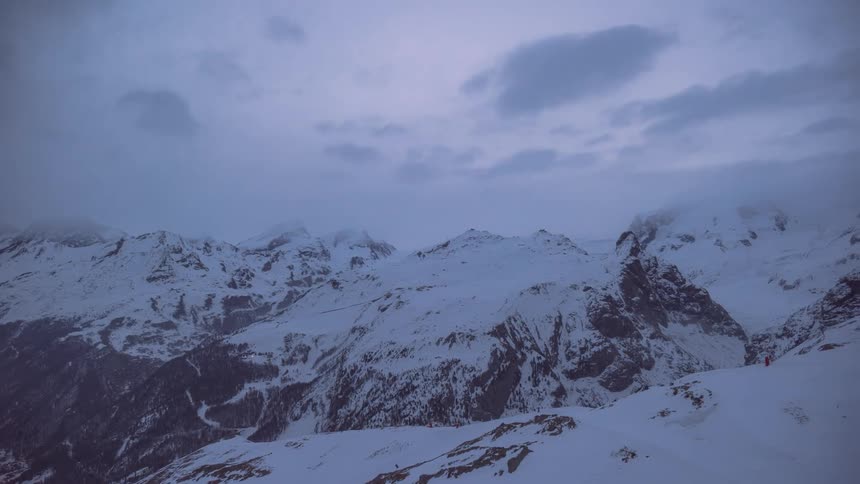 A time lapse of clouds over a mountain range covered in snow