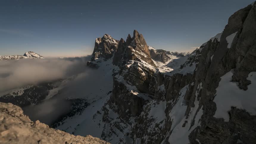 Dense cloud banks gather and disperse around snowy mountains