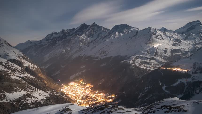Snowy mountain range in a village illuminated in the background