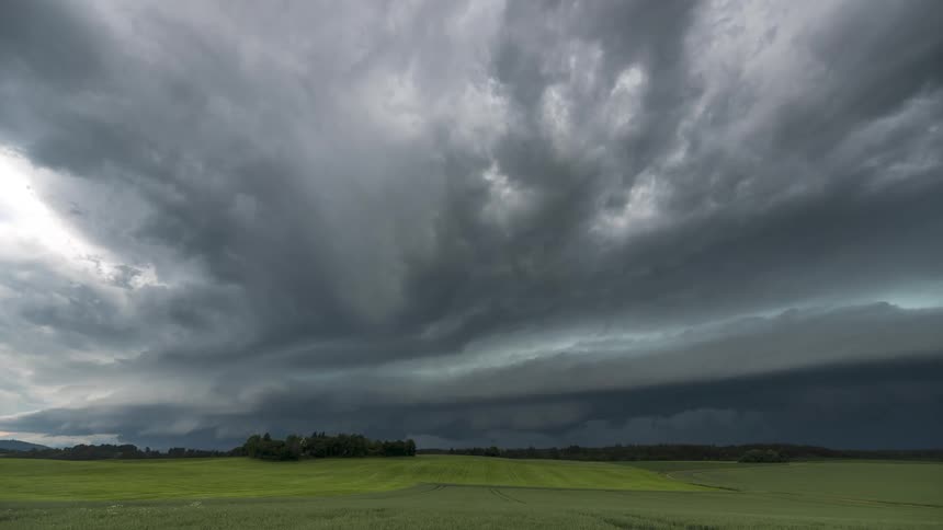 Storm clouds move over a forest and agricultural fields