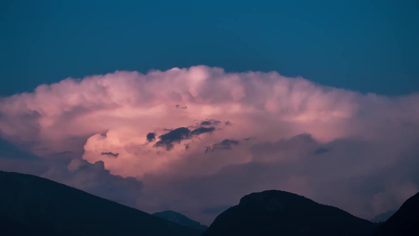 A giant storms with lightening occurring over a mountain range