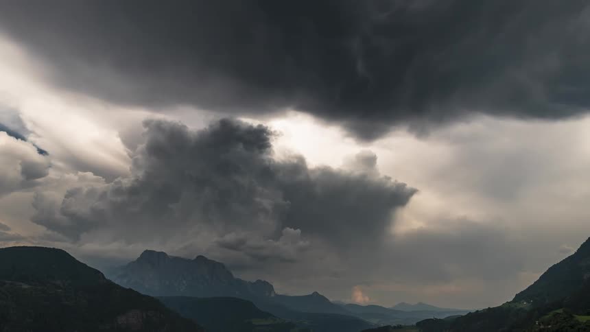 Big storm clouds expand and fill the sky over mountain ranges