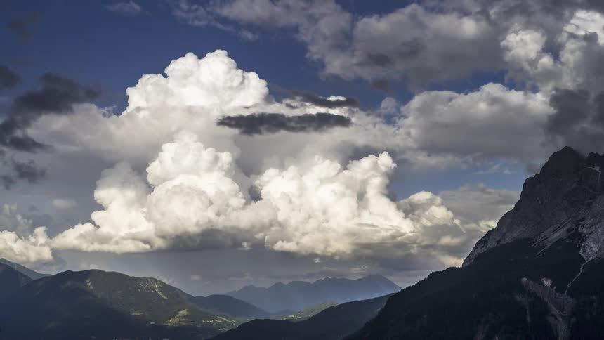 Thick clouds over mountain ranges turn dark with storms