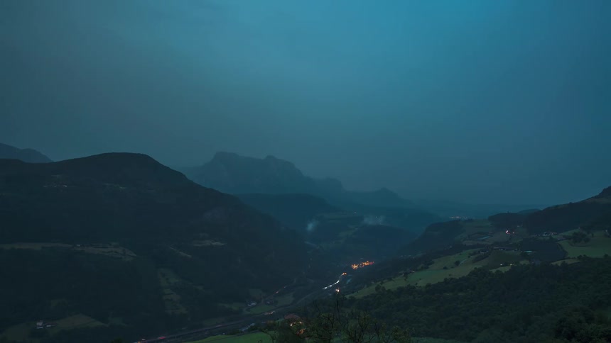 A lightning storm occurs in a rural mountain community at dusk