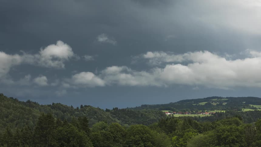 Time lapse of storm clouds rolling over a rural landscape in the hills