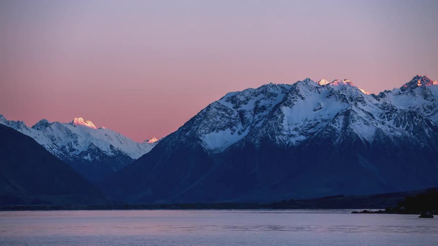 Lake surrounded by snowy mountains in an early morning