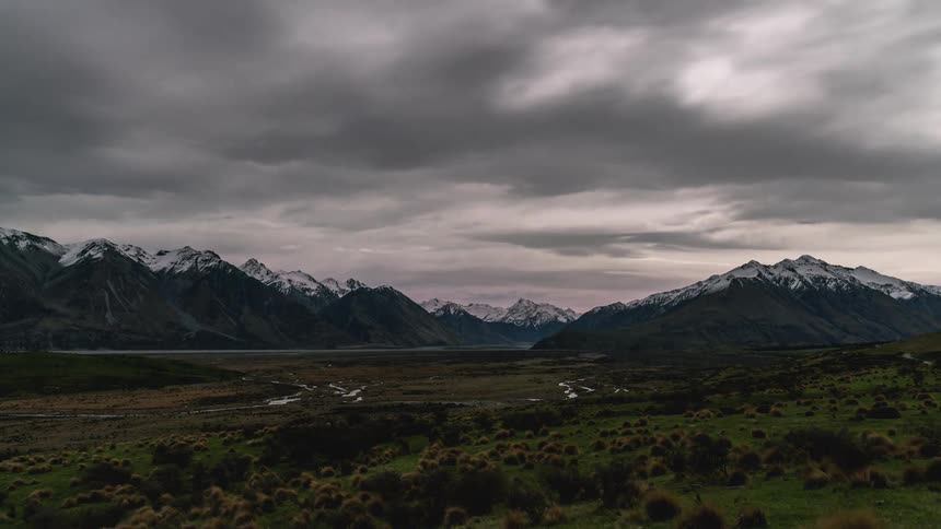 Natural landscape with animals passing by the edge of snowy mountains on a day with dawn and dusk sky