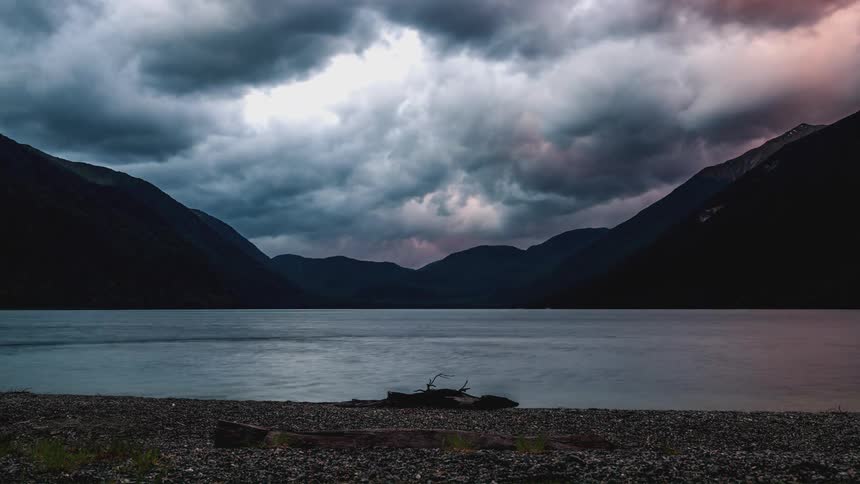 Time lapse of colorful clouds rolling over a lake in the mountains