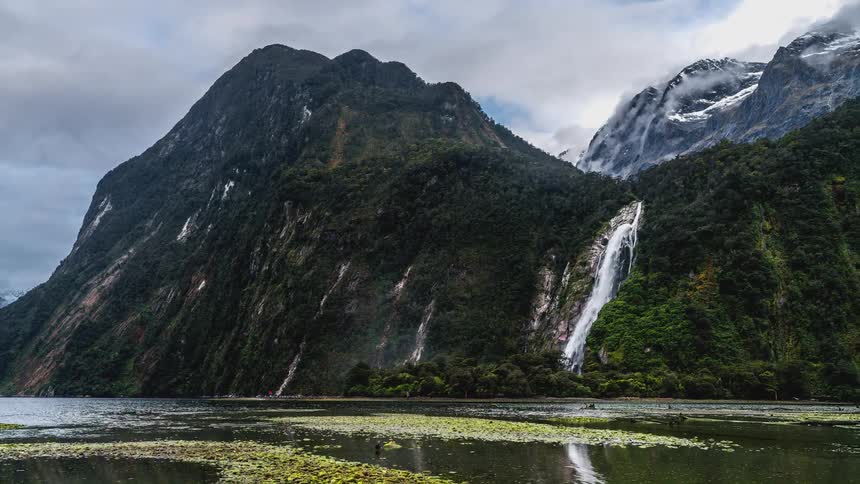 Natural landscape of mountain ranges with waterfalls and a flowing lake