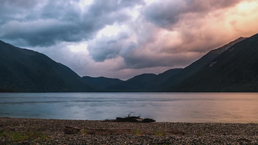 Lake surrounded by mountains silhouette on a cloudy day
