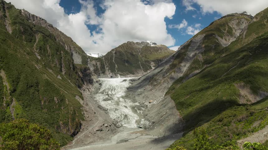 Clouds cast moving shadows over a mountain pass