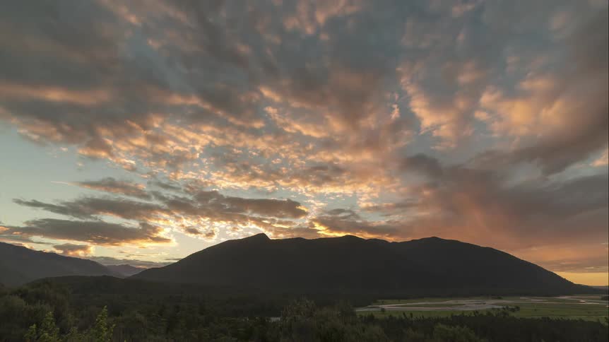 Time lapse of clouds rolling over a mountain at sunset