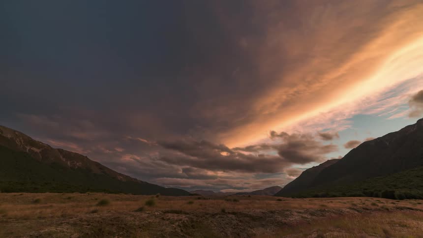 Landscape of a field surrounded by mountains and the day getting dark