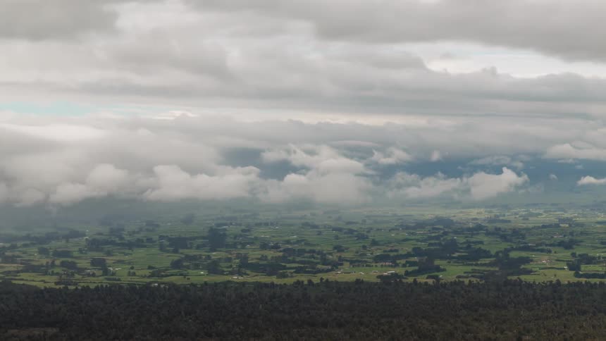 Time lapse of clouds rolling over a landscape of green fields and small houses
