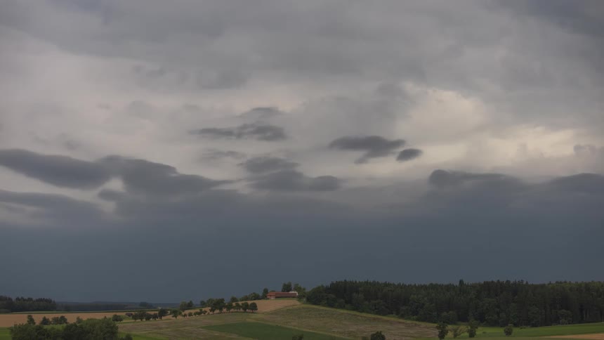 Landscape of a field with forests and in the background a sky with clouds