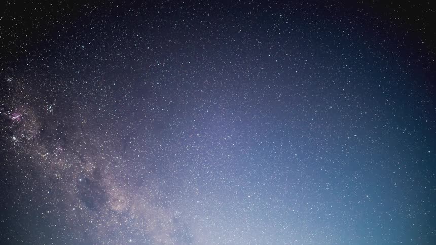 Lake surrounded by mountains against a starry night sky