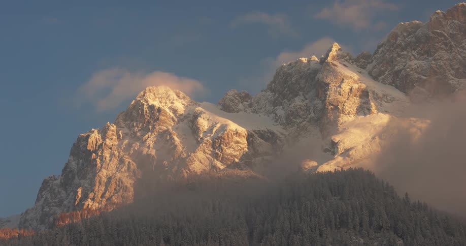 Mountain range covered by snow with conifers around and on a morning