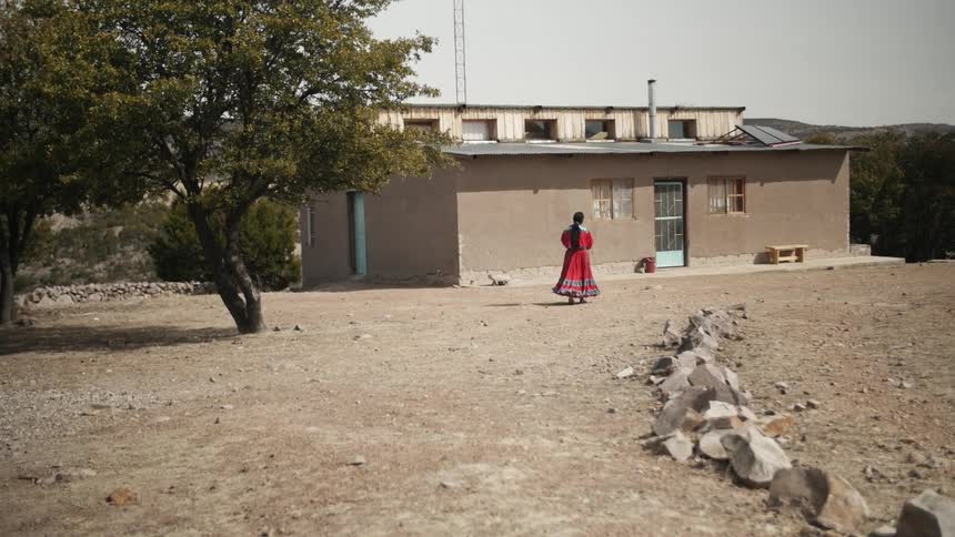 A woman in native dress walks toward a building
