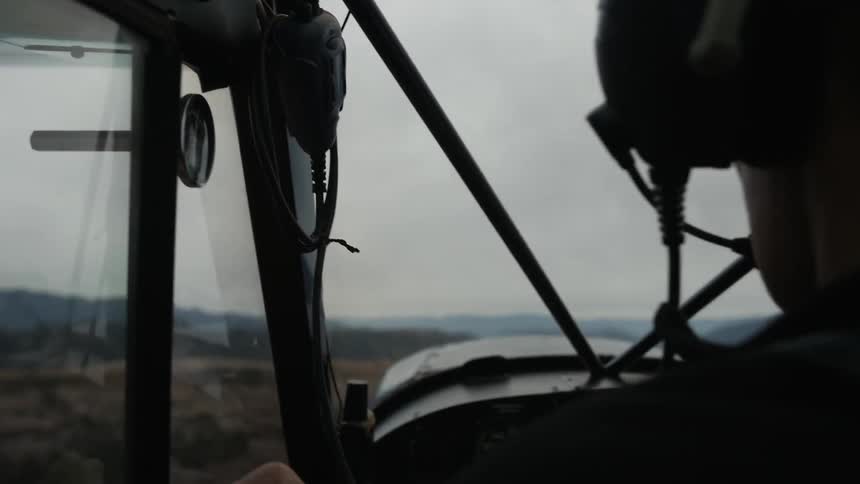 A pilot is flying an airplane during the day