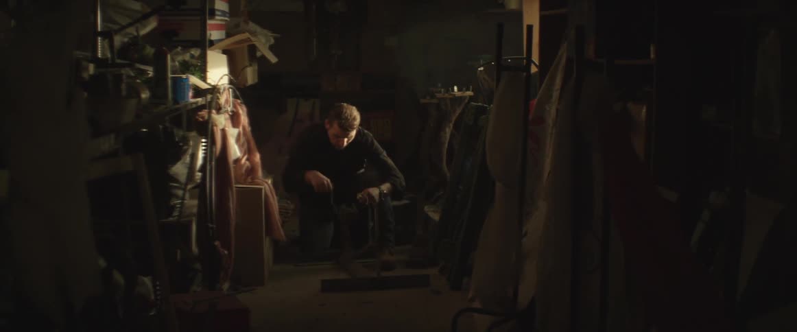 A man sits in a shop and works a piece of equipment
