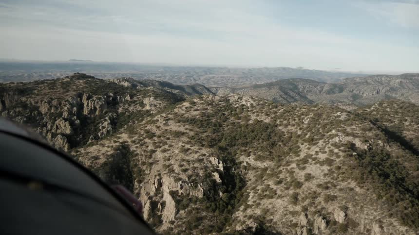 A helicopter flies over mountains