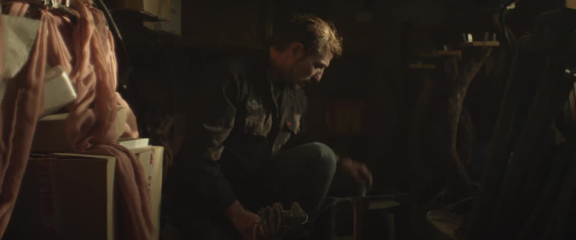 A man sits in a shop and works a piece of equipment