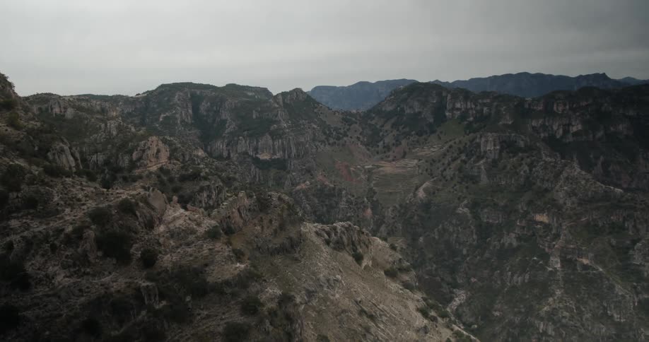 A mountain canyon stretches toward the horizon under a cloudy sky
