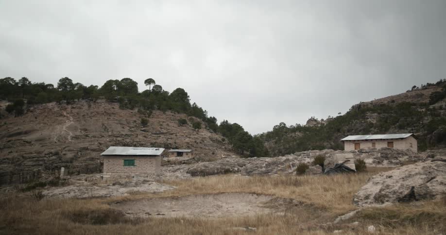 A few small buildings sit on this mountain range on a cloudy day