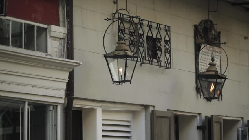 A gas lantern burns as it hangs from a building