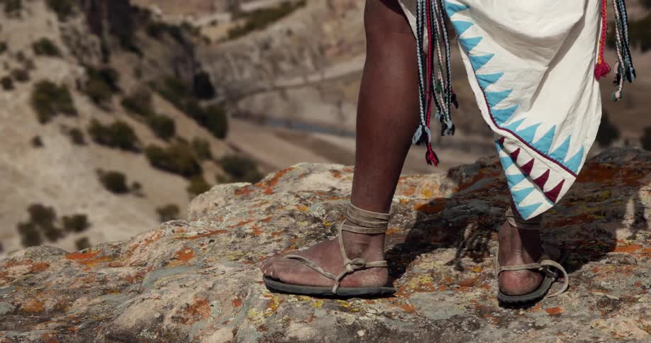 A person in sandals stands at the edge of a cliff