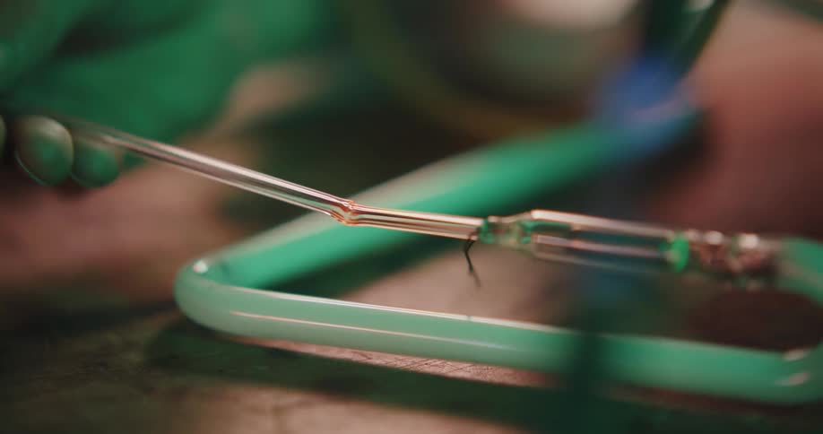 A man shapes neon lightbulb glass using a flame tool