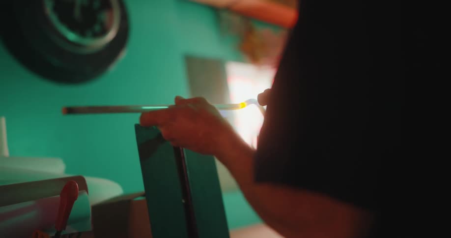 A worker heats up a long tube indoors