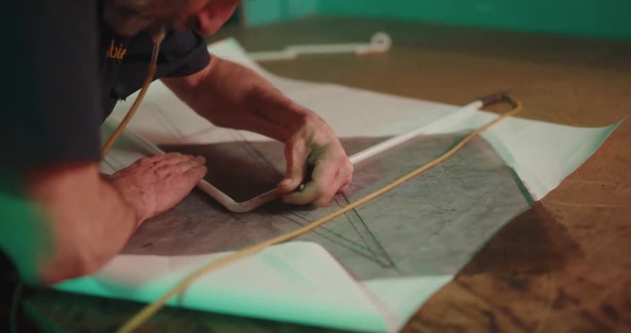 A man using a paper blueprint to design a neon light