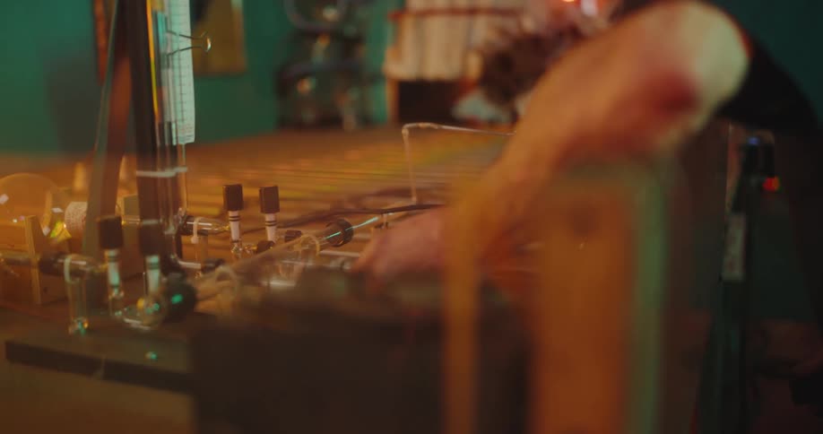 A face of an adult man who is fiddling with some pipes and tubes on a table with his hand