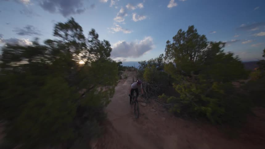 Person riding a mountain bike through a canyon on the edge of a cliff