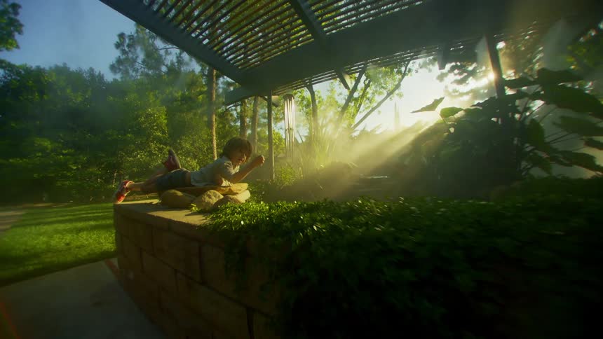 Boy lying on rocks at the edge of a body of water surrounded by vegetation