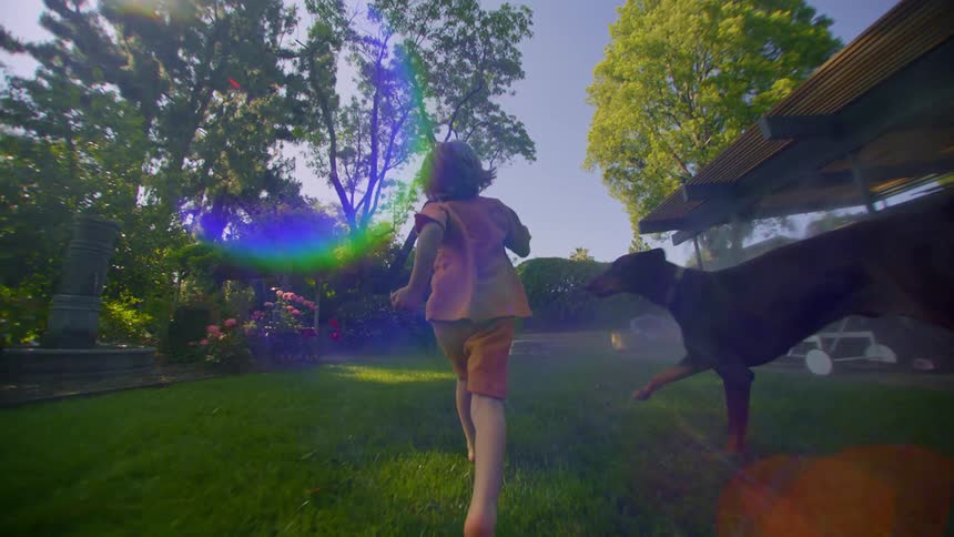 Little boy running in the backyard with his dog by his side