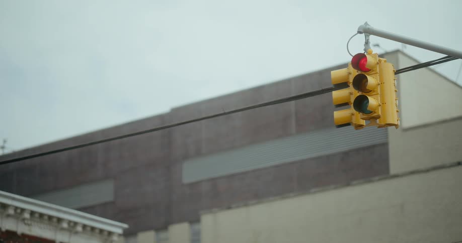A hanging traffic light turns from red to green in a city
