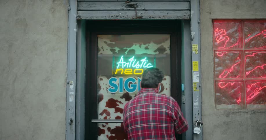A man walks into a shop that sells neon signs