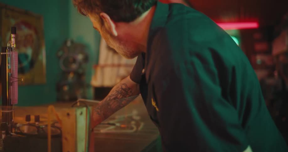 A man using a dial device to turn a neon light off and on, as well as vary its intensity,