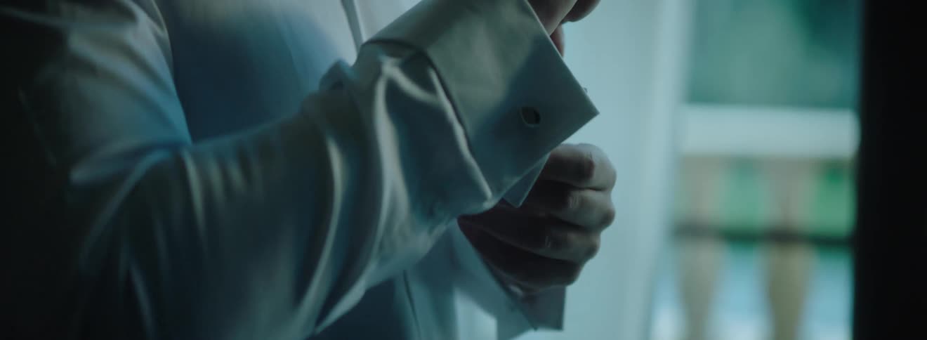 Man buttoning his dress shirt on his sleeve