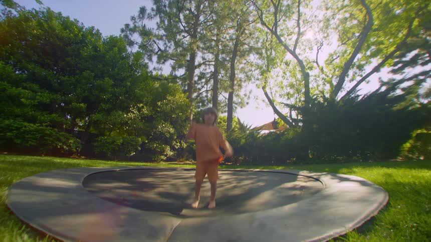Dog runs across the side of the low profile trampoline a child is bouncing on
