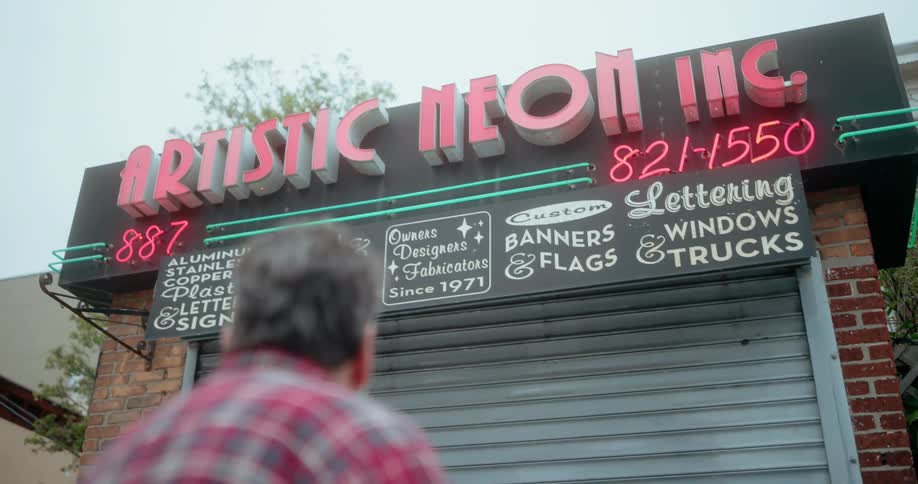A man stands outside looking up at a shop front