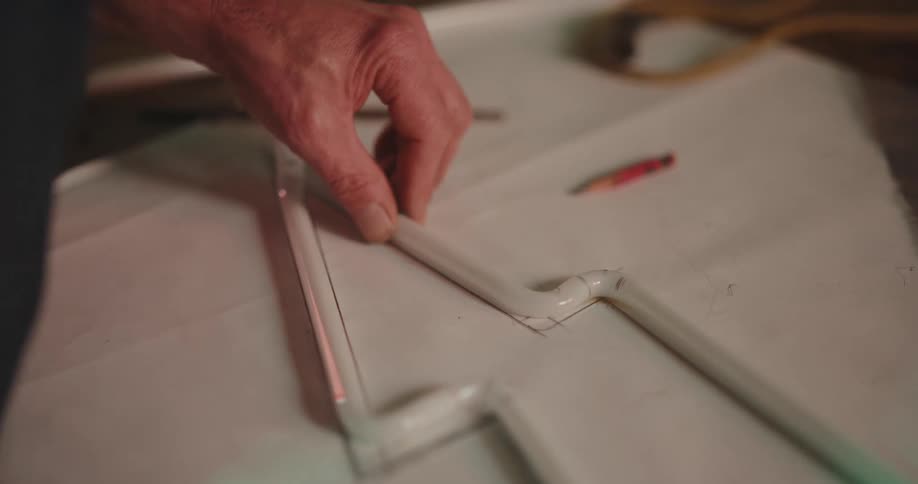 A mans hands are shown measuring on a large piece of paper