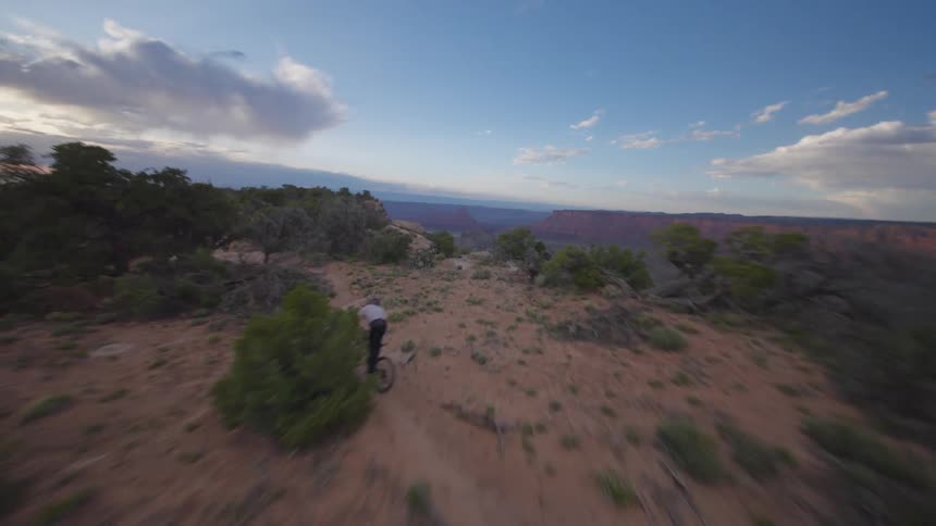 Person riding a mountain bike in a canyon on the edge of a cliff