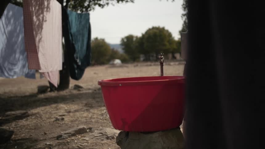 A red basket appears empty while sheets hang on the line nearby