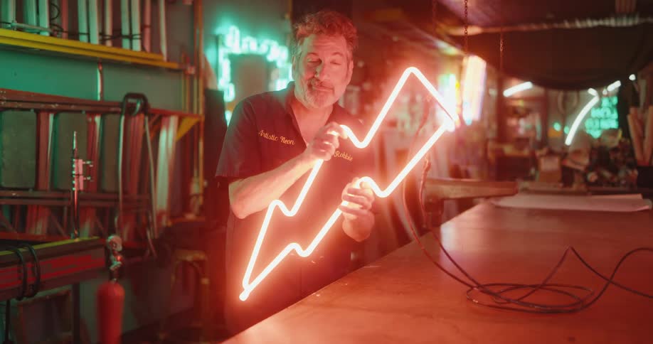 Man showing a sign of a lightning symbol in neon with red lights