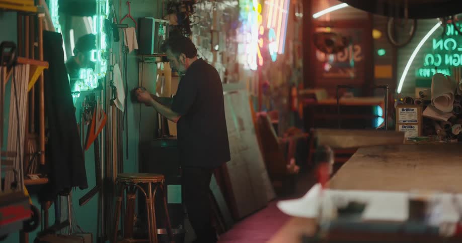 Man pulling a wire while indoors with walls decorated with neon lights