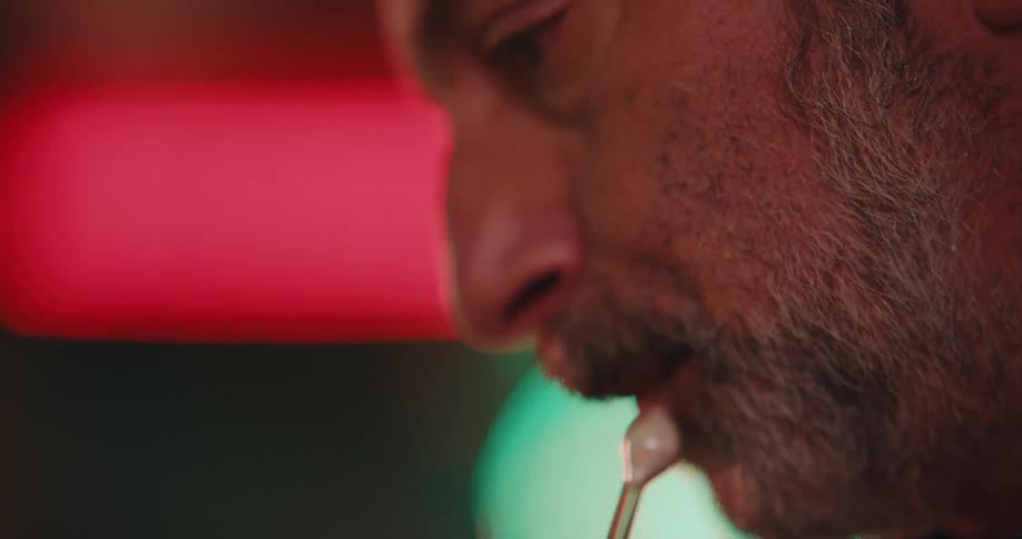 A man shaping glass using a blowtorch whilst simultaneously blowing into a tube
